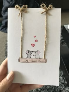 someone holding up a card with two elephants on it and hearts in the sky above them