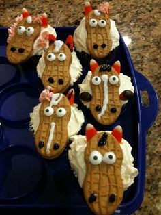 some cupcakes with icing and eyes are in a blue tray on the counter