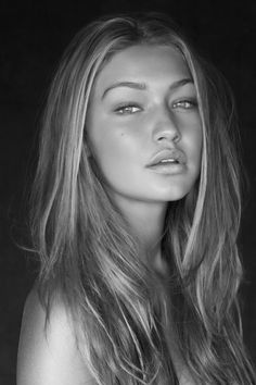 a woman with long hair is posing for a black and white photo in front of a dark background