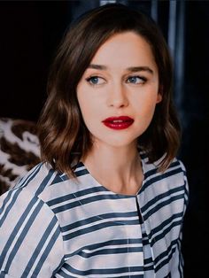 a woman with red lipstick is wearing a striped shirt and has dark blue eyeshadow