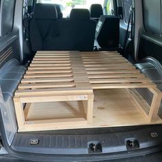 the back end of a van with two wooden shelves on it's cargo area