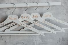 three personalized wooden hangers with names on them hanging from a white coat rack