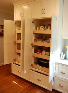 an open pantry door in a kitchen with wooden floors and white cabinets on both sides