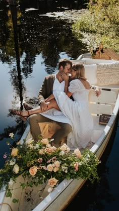 a man and woman are sitting in a boat on the water with flowers around them