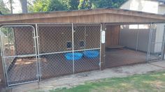 a dog kennel with two blue plastic bowls in the center and a fence around it