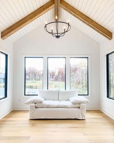 a living room with three windows and a white couch in the middle of the room