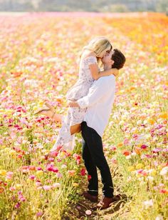 a man and woman kissing in a field of flowers