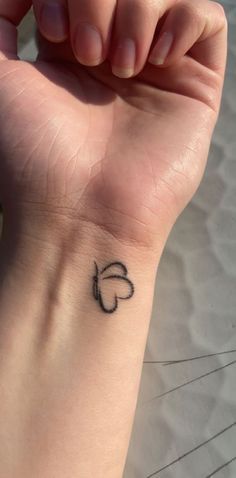 a woman's wrist with a small heart tattoo on the left side of her arm