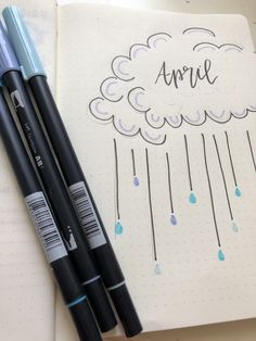 two pens sitting next to each other on top of a notebook with an umbrella drawn on it