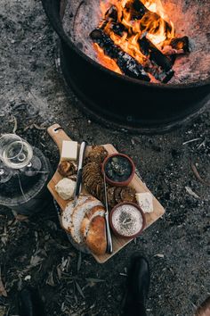 a campfire with bread and wine on it next to a plate full of food