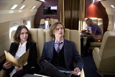 two people are sitting in the back of an airplane and one person is holding papers