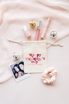 various items are laid out on a white sheet next to a bag with the words happy valentine's day written on it