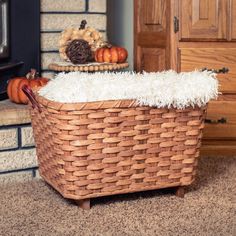 a wicker basket sitting on the floor next to a fire place with pumpkins