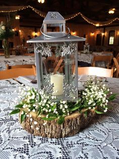 a candle sits on top of a piece of wood with flowers and greenery around it