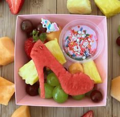 a pink bowl filled with fruit and candy