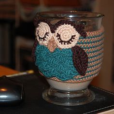 a crocheted owl mug cozy sitting on top of a computer mouse