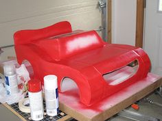 a large red chair sitting on top of a table next to bottles and other items