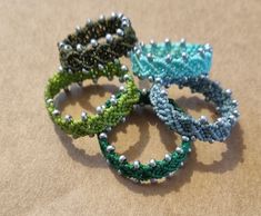 three bracelets with beads are sitting on a table together, one is green and the other is blue