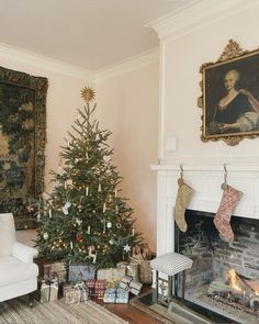 a living room with a christmas tree in the corner and stockings hanging on the fireplace