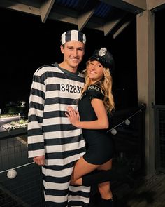 a man and woman dressed up in jail uniforms posing for a photo together at night