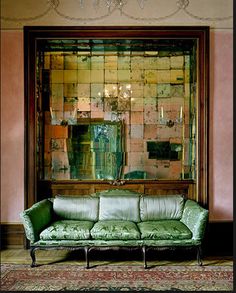 a green couch sitting in front of a mirror