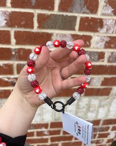 a woman's hand holding a red and white beaded bracelet