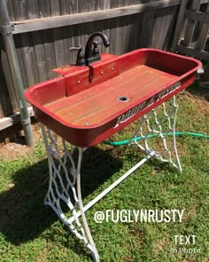 an old fashioned red sink sitting in the grass