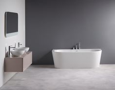 a white bath tub sitting next to a sink in a bathroom under a mirror on the wall