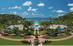 an aerial view of a resort with palm trees and boats in the water behind it