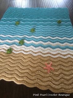 a crocheted blanket with shells and starfish on it