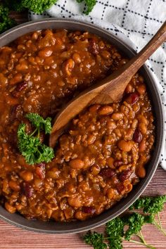 a wooden spoon in a pot filled with baked beans