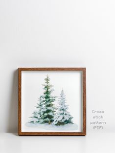 a small wooden frame with a painting of trees in the snow on top of it