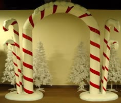 three candy canes are on display in front of christmas trees