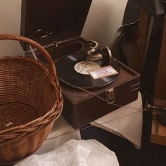 an old record player sitting on top of a table next to a wicker basket