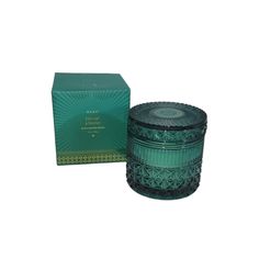 a green glass candle next to a box