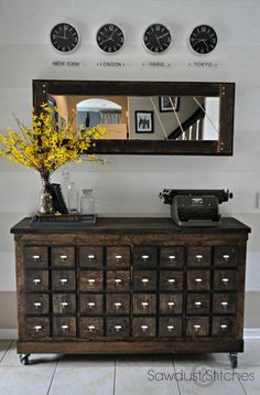 an old dresser with drawers and a clock on the wall above it is decorated with yellow flowers