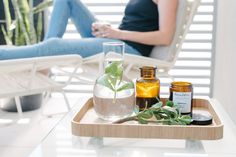 a woman sitting on a white chair next to some bottles and plants in front of her