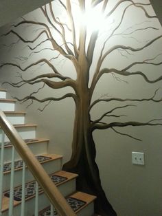 a tree painted on the wall next to stairs