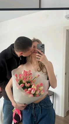 a man taking a selfie while holding a bouquet of tulips