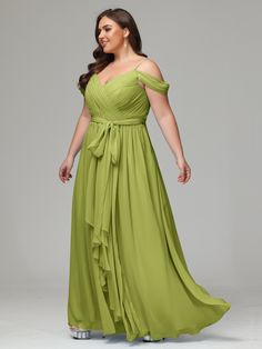 a woman in a long green dress posing for the camera with her hands on her hips