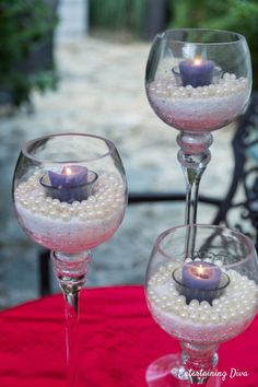 two wine glasses with candles in them on a table