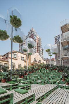 an outdoor area with wooden benches and potted plants in the foreground, surrounded by tall buildings