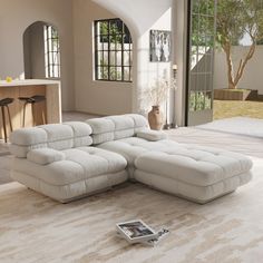 a large white couch sitting on top of a living room floor next to a window