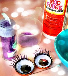 two fake eyelashes sitting on top of a table next to a jar of glue and a spoon