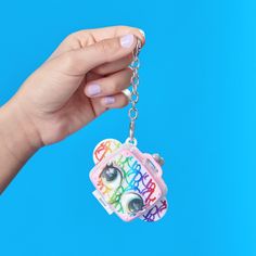 a hand holding a keychain with the words happy birthday on it and a camera attached to it