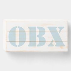 a wooden sign with the word obx painted in light blue on it's side