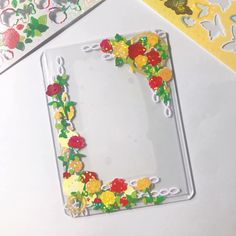 a plastic frame with flowers and scissors on it next to other paper crafts that are cut out