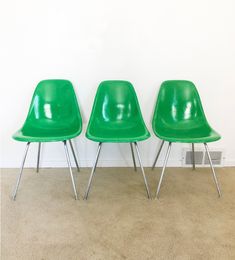 three green chairs sitting next to each other on carpeted floor in front of white wall