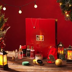 a red box with christmas decorations and lights on it sitting on a wooden table in front of a tree