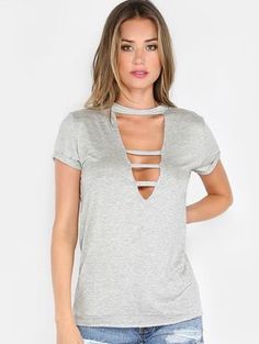 a woman in ripped jeans and a grey shirt with a cut - out neckline